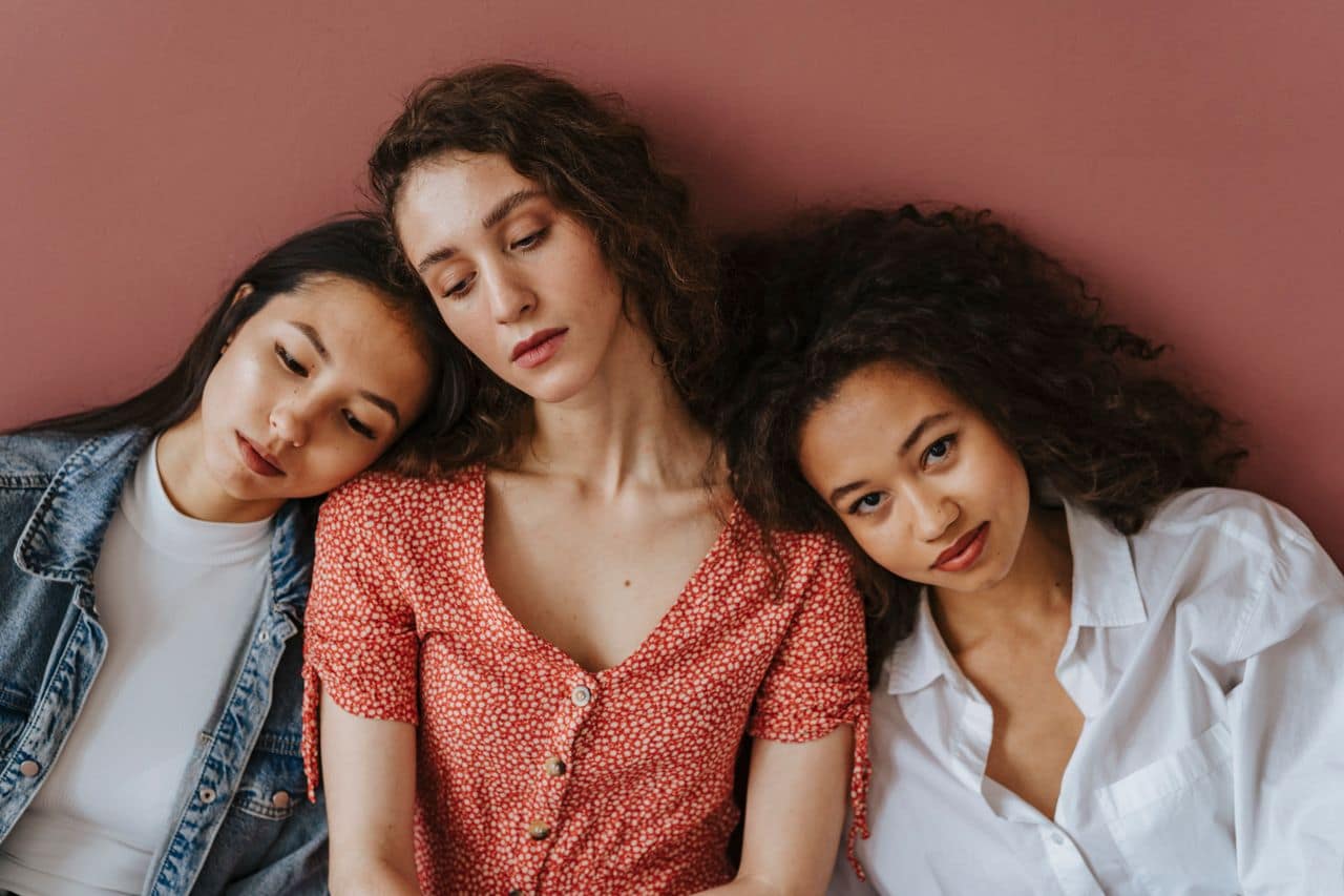 A diverse group of women sitting and leaning together, showcasing friendship and unity.