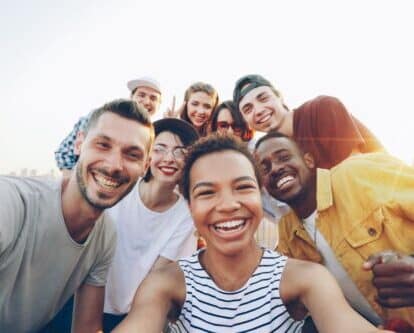 A diverse group of friends taking a joyful selfie outdoors during sunset.